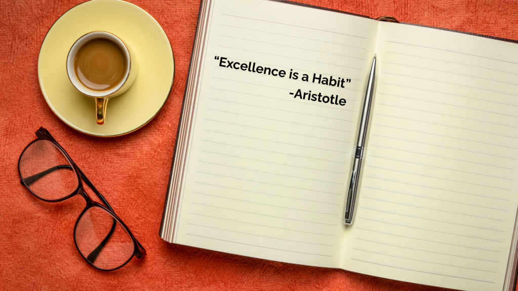 Open notebook with a pen displays the quote "Excellence is a Habit" - Aristotle. Nearby are a cup of coffee and eyeglasses on an orange surface.